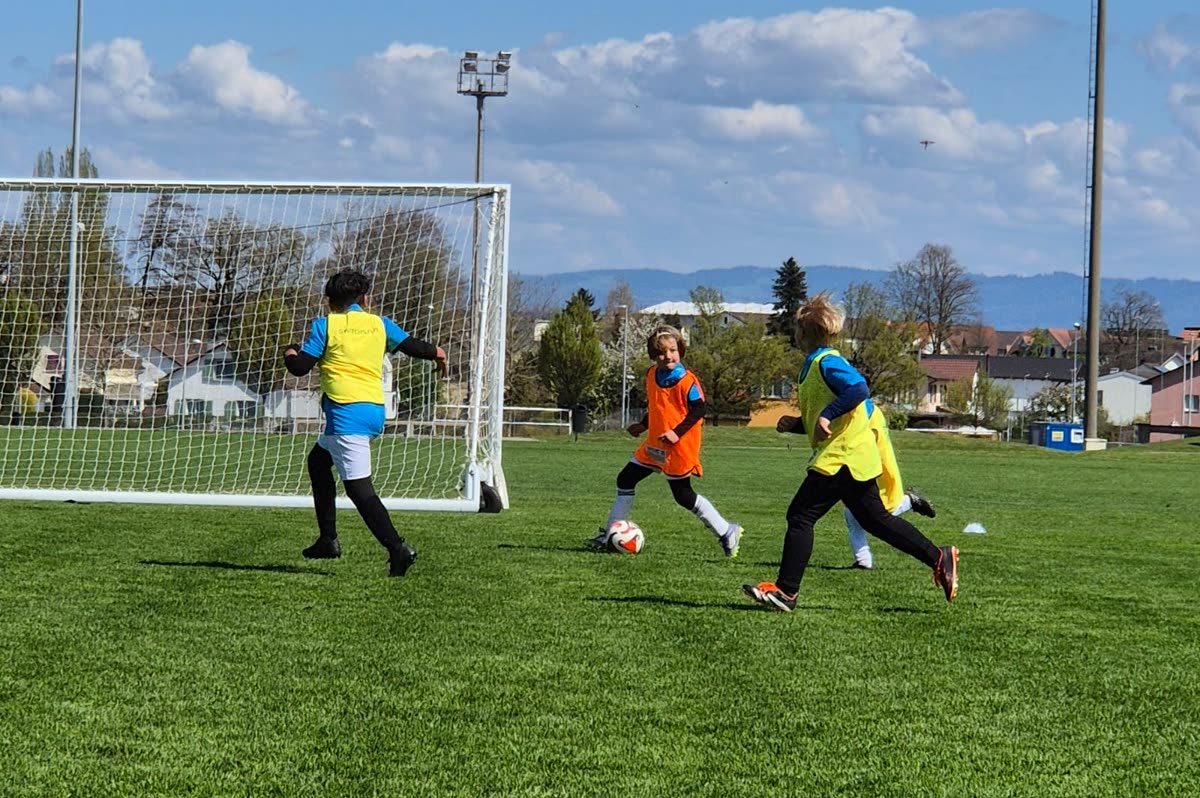 Spielszene vor dem Tor: ein Kind am Ball, zwei setzen nach