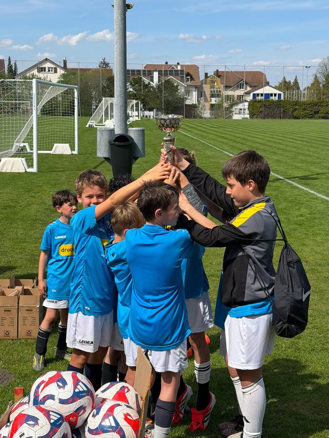 Kinder strecken gemeinsam einen Pokal in die Höhe